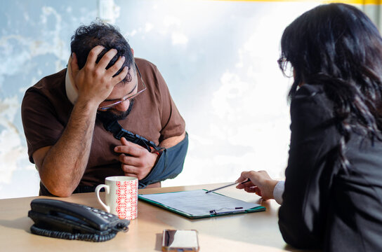 Young female lawyer assist a injured man with legal problem. Lawyer showing document. Compensation for work or car accident. Legal concept. Social Worker.