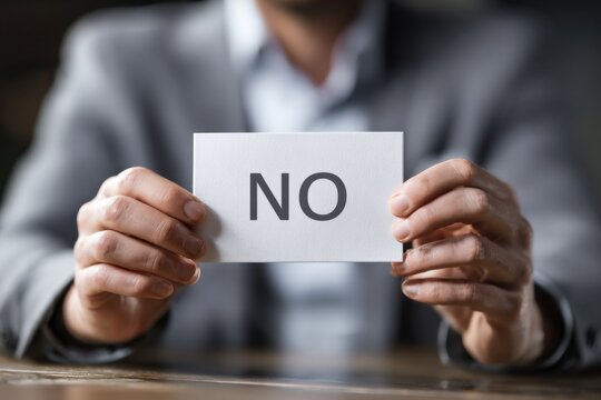 A Person Holding a Sign That Says 'NO' in a Professional Setting, Conveying Rejection or Dissent Amidst a Corporate Environment