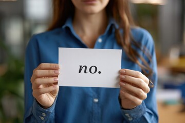 A woman confidently holds up a card displaying the word 'no', symbolizing assertiveness and the importance of setting boundaries in personal and professional life.
