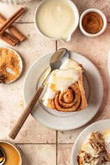 Freshly baked glazed cinnabon buns in ceramic plates, beige tile background. Cinnamon rolls serving, top view