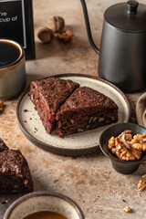 Chocolate spongy brownie cake with walnuts and coffee on brown table background. Two pieces of chocolate brownie cake