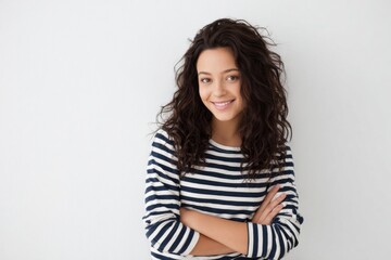 Obraz premium Cheerful young woman smiling with curly hair wearing striped shirt against white background.