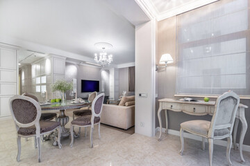 An elegant and stylish living room with a dining area and a work space in a bright, modern apartment.