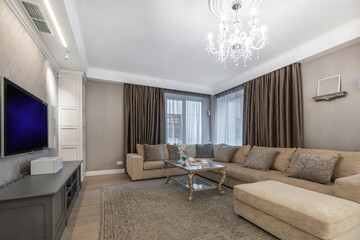 The refined interior of the living room features a modern sofa and a luxurious chandelier in a well-lit apartment.