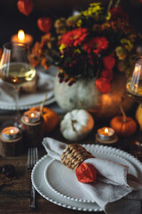 Atmospheric autumn elegant beautiful table setting with pumpkins for a wedding or thanksgiving family celebration. Fall decoration countryside rustic style, cozy home atmosphere , candles, wine