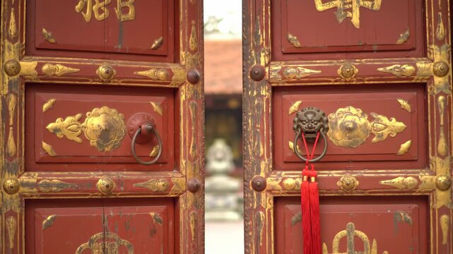 Glimpse Through Ornate Red Chinese Temple Doors into a Sacred Courtyard with a Passerby.