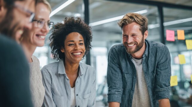 Diverse group of smiling young adults collaborating and discussing in modern office space. - Powered by Adobe