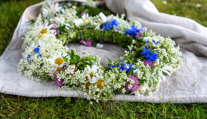 Floral crown made of wildflowers and greenery rests on soft fabric, symbolizing traditional celebration during solstice festivities in Latvia, showcasing cultural heritage and craftsmanship