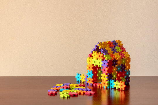Colorful puzzle house falling apart on wooden table