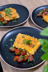 Creamy macaroni and cheese served on black plates with cherry tomatoes and fresh herbs, showcasing a delicious comfort food meal with vibrant colors and textures