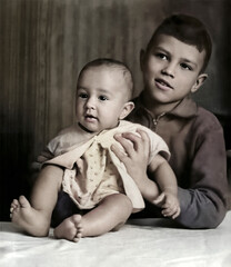 A vintage portrait of two siblings. The older brother is holding a one-year-old boy. Retro photo from the 1960s.