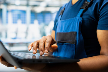 African american expert troubleshooting photovoltaic systems in solar power plant, working on a PC software for designs. Technician examines configurations in renewable energy operations.