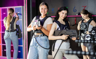 Two woman in the special vests holding laser guns and playing laser tag with girlfriends on the...