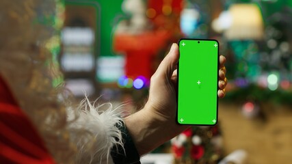 Santa Claus bringing joy to others during holidays, posting online on isolated screen smartphone. Santa Claus using mockup phone to spread sense of wonder during Christmas, camera A close up