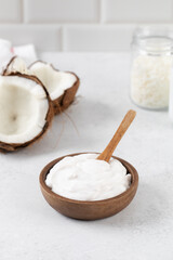 Fresh coconut yogurt in a wooden bowl with a wooden spoon and coconuts. Plant yogurt, lactose-free.