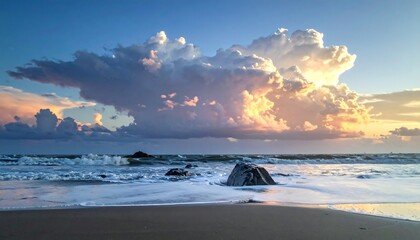 Dramatic sunset over ocean waves crashing on sandy shore, rocks in foreground