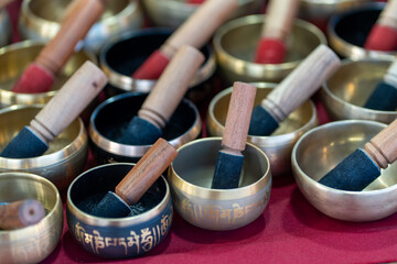 Various standing bells with wooden mallets are artistically arranged at a market stall. The vibrant colors and unique designs invite visitors to explore their calming sounds and spiritual uses.