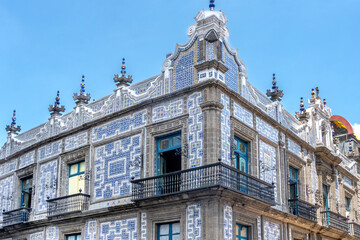 A building with blue and white tiles on the side. The building has a lot of windows and balconies. Casa de los azulejos, Mexico City, Zocalo, historic building
