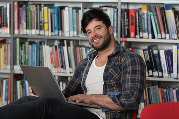 Male Student Typing on Laptop in the University Library