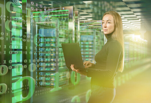 IT specialist with laptop monitors servers in data center with digital code overlay, ensuring cybersecurity and network operations. Activity: IT, Data Center, Cybersecurity. - Powered by Adobe