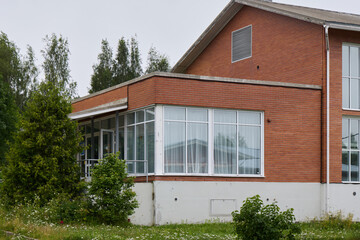 A Charming Brick House Featuring a Beautiful Glass Enclosure Surrounded by Lush Greenery