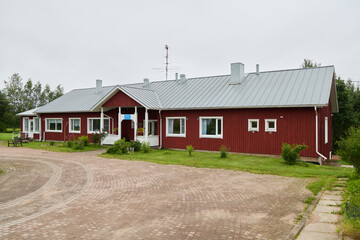 Charming Red Wooden Building Featuring a Metal Roof Surrounded by Lush and Beautiful Greenery