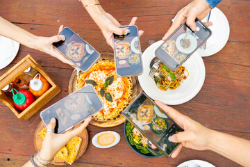 Group of Happy Asian man and woman using mobile phone taking picture food and drink on dining table. People friends enjoy and fun meeting celebration holiday event dinner party together in the garden.