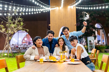 Portrait Group of Happy Asian millennial people friends enjoy meeting holiday celebration social gathering dinner party in garden evening, drinking beer and talking together outdoor festive event.