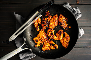 Cooked Marinated Chicken Strips in a Frying Pan: Cooking chicken breast marinated in red curry paste mixture in a non-stick skillet