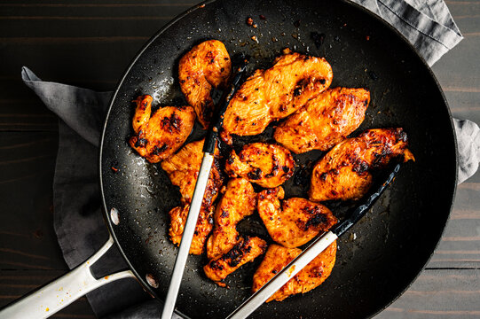 Cooked Marinated Chicken Strips in a Frying Pan: Cooking chicken breast marinated in red curry paste mixture in a non-stick skillet