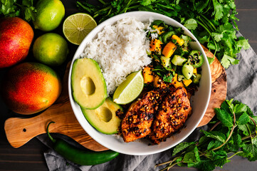 Chili Crisp Chicken Mango Rice Bowl Overhead: Spicy chicken breast strips served with white rice, mango herb salad, avocado, and a lime wedge