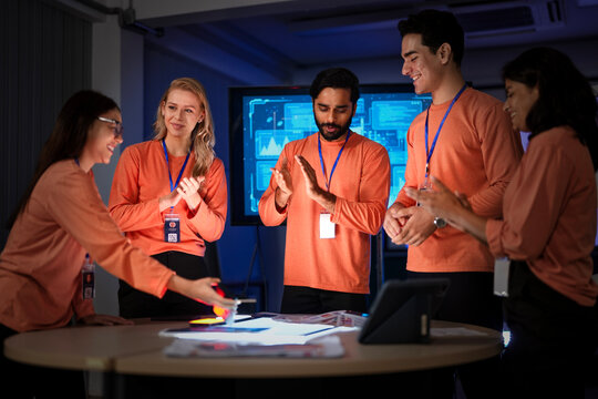 A development team shows satisfaction after a successful product launch. They are reviewing the final app on their smartphones, celebrating a flawless execution of their project.