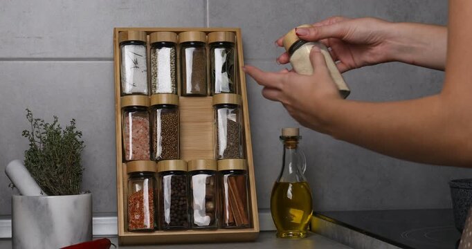 Woman taking garlic powder in glass jar in kitchen, closeup