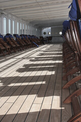 Sun or pool deck with elegant teak wood deck chairs and loungers onboard outdoor Belle Epoque patio terrace of luxury cruiseship or cruise ship liner