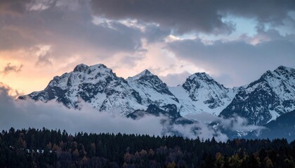 Snow Capped Mountain Peaks Under Cloudy Sky At Sunset With Silhouette Of Trees In Foreground