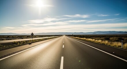 Fototapeta premium Sun-Kissed Asphalt: A Long Road Stretches Through Arid Landscape