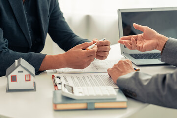 Real estate agent showing house plans to clients. Agent during meeting with interested clients,...