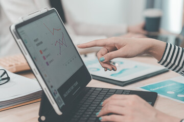 Two businesswomen having a meeting and looking at financial data, charts and graphs on a digital tablet. Business consultant analyzing financial figures.
