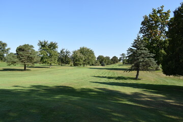 Looking down a tree lined golf course fairway towards the putting green.