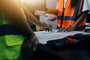 Closeup of team of industrial engineers meeting analyze machinery blueprints consult project on table in manufacturing factory. Working in manufacturing plant or production plant.