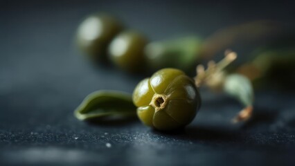 Close-up of dark-green, round, seed-like fruits on a dark surface