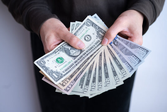 Cropped shot view of woman holding various of American dollar banknotes in hands. The US Dollar is the currency of United States.