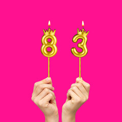 Hands holding number shaped candles - Birthday number 83