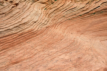 Waves of layers of orange stone eroded out of rock layers of orange sandstone rock wall, patterns and texture in nature, Zion National Park, Utah
