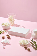 Top view pink setting with shadows, creamy shea butter on glass bowls, shea nuts, leaves and butter. Perfect for minimal nature-inspired product showcase mockups. Empty podium for display