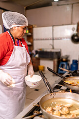 Woman chef preparing fried food in restaurant kitchen