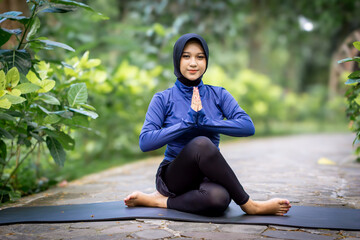 Healthy Asian woman in sportswear do yoga at the park. Moslem woman with sportwear.