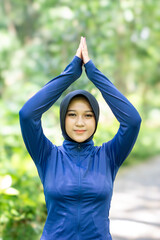Healthy Asian woman in sportswear do yoga at the park. Moslem woman with sportwear.