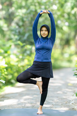 Healthy Asian woman in sportswear do yoga at the park. Moslem woman with sportwear.