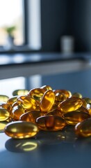 A close-up view of a pile of golden-amber colored capsules, glistening with light, on a smooth, gray surface.